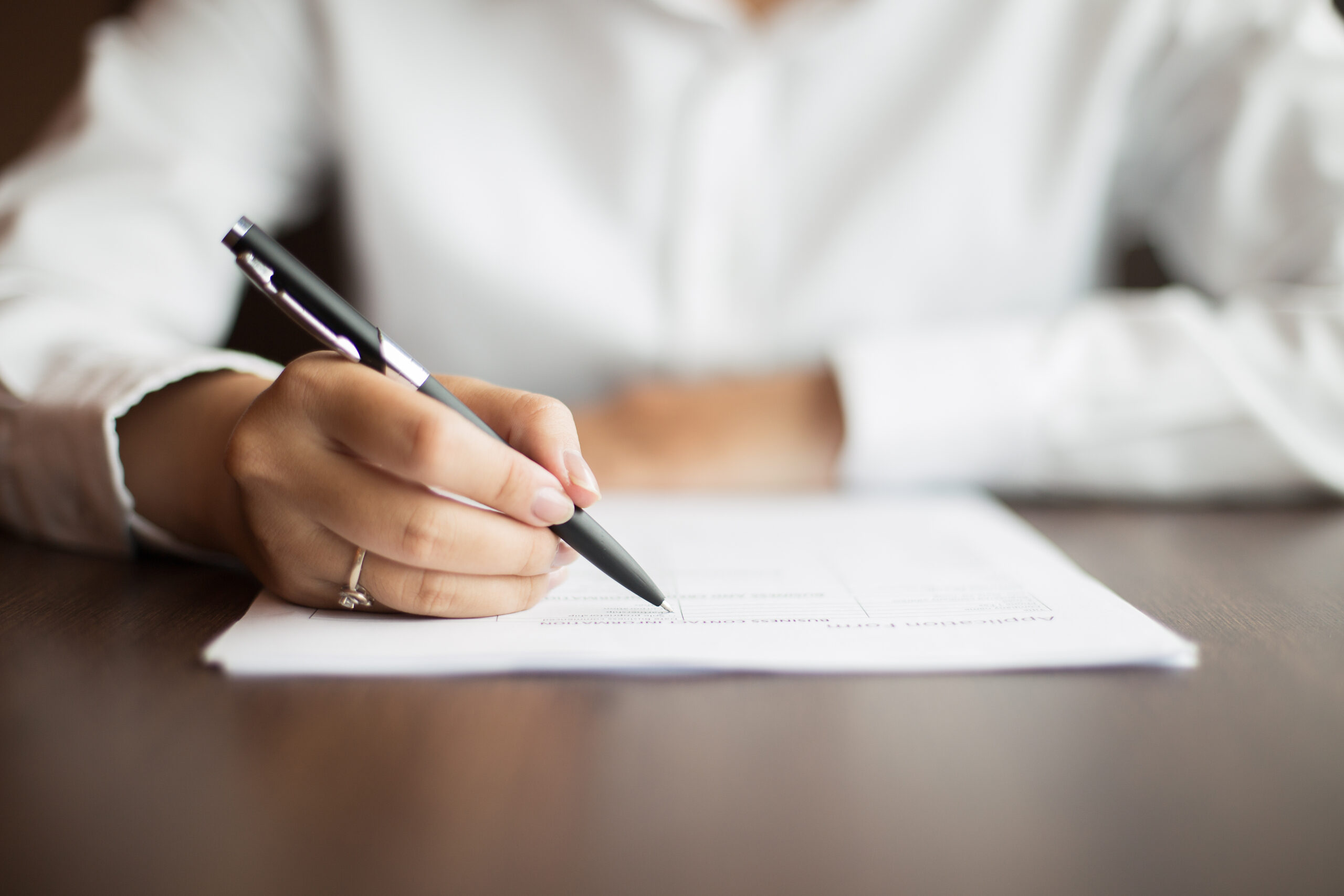 Hand of businesswoman writing on document at table